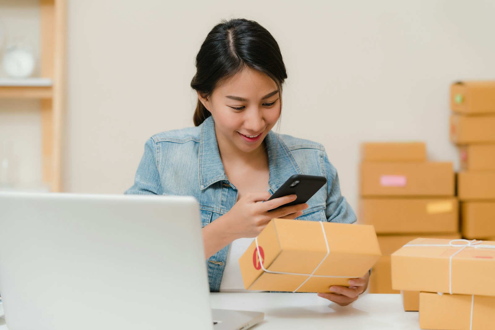 A shopper checking a delivery package next to her laptop